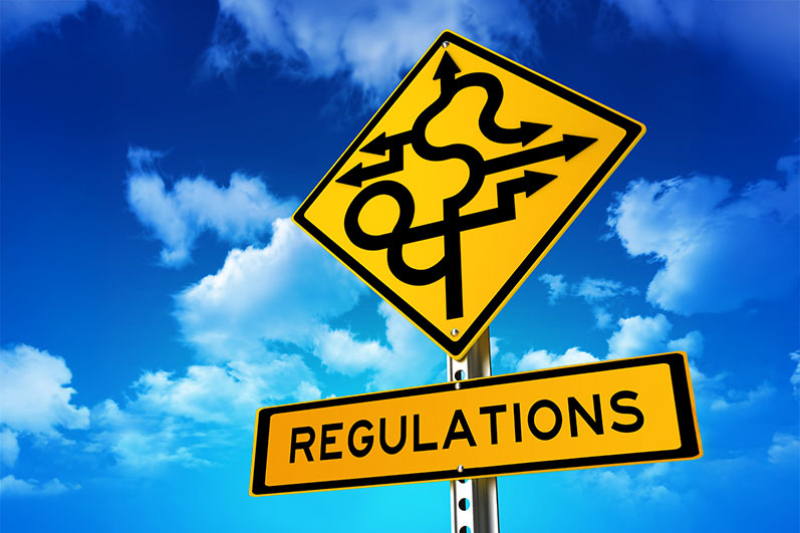 Image of a yellow road sign with complex directional arrows, and another sign below it that says REGULATIONS.