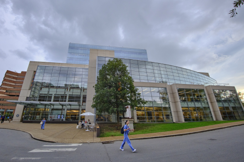 Medical Student walking in front of a medical building.